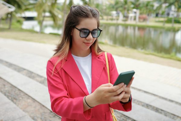 Smiling Woman in Pink Blazer Using Smartphone Outdoors